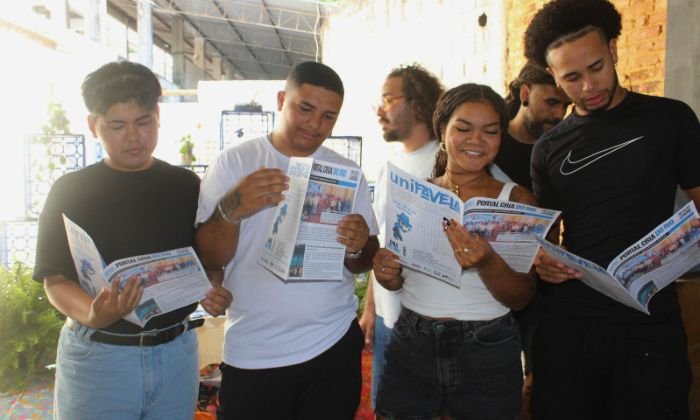Grupo de jovens lendo um jornal impresso