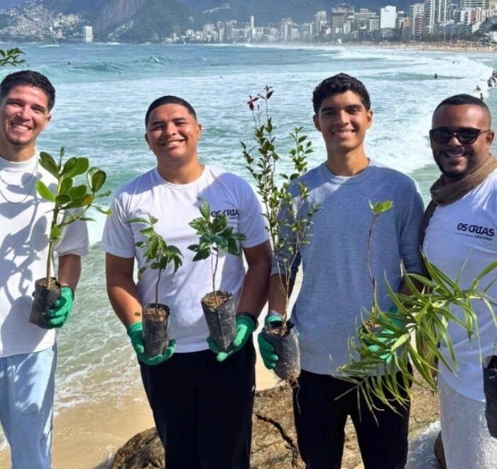 Grupo segura mudas de plantas na praia